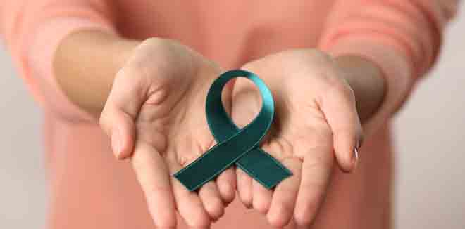 Close up view of female hands holding sea-green ribbon. Ovarian cancer and gynecological disorders concept