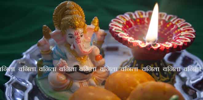 Indian sweet laddu with prayer lamp and Ganesha statue