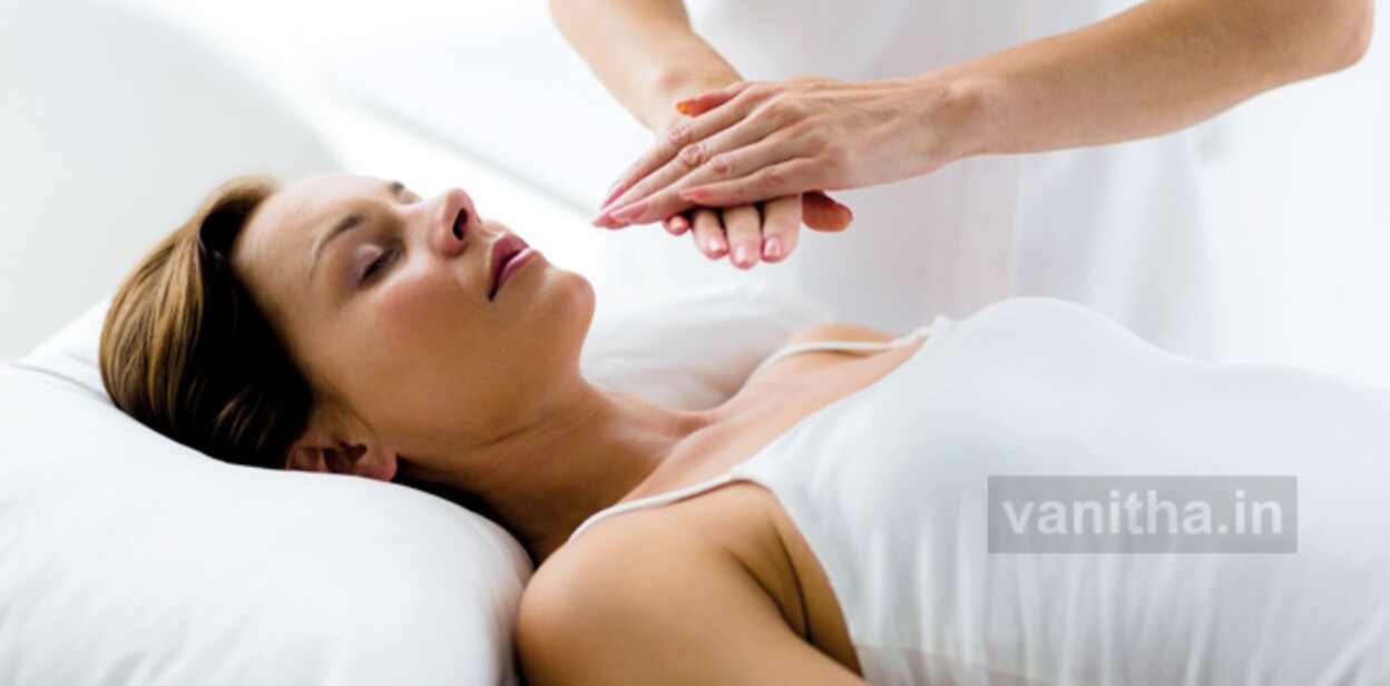 Theparist performing reiki treatment on woman