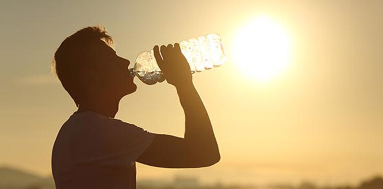 Fitness man silhouette drinking water from a bottle