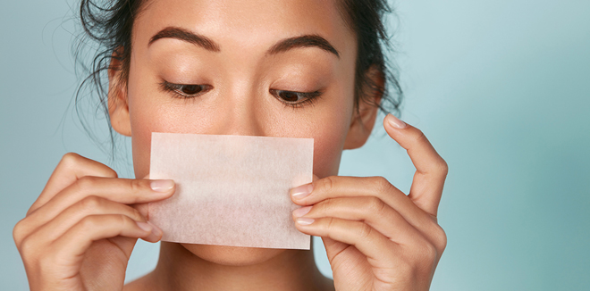 Skin care. Woman holding facial oil blotting paper portrait
